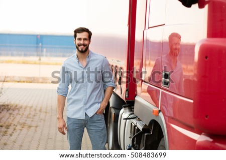 smiling handsome masculine driver stranding next to his red truck outside