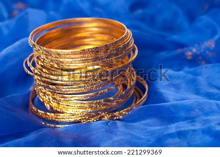 Thin gold bangles put on a blue textile