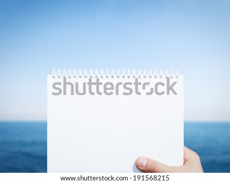 horizontal white blank notebook in man hand with sea background
