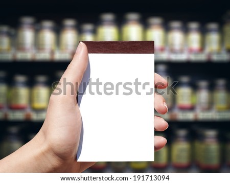 white blank vertical notebook in woman hand and pharmacy background