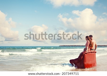 couple resting on leather couch on the beach