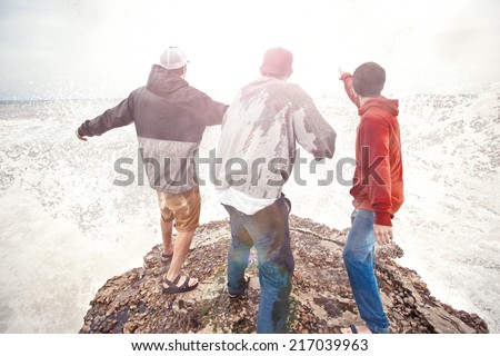 three brave men standing on a cliff in storm