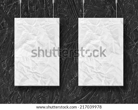 two hanging crumpled lists of paper and wooden background