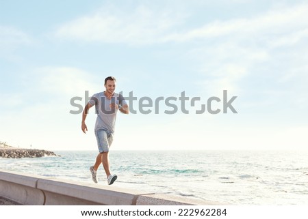 young man walking over the pier near the ocean with earphones and music