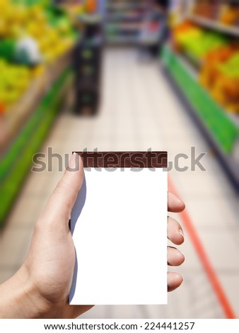 white blank vertical notebook in woman hand and supermarket background