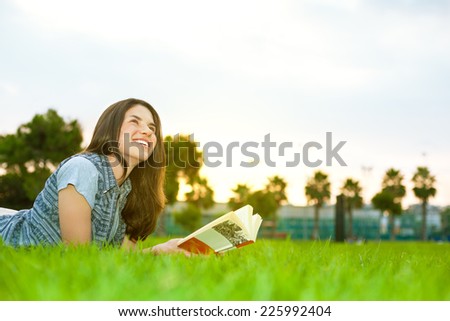 young and beautiful woman on the grass with a book