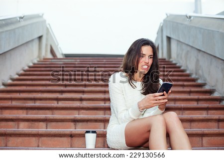 angry beautiful woman sitting on the stairs with mobile phone and cup of coffee