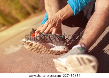 sportsman tie shoelaces on his running shoes in the park