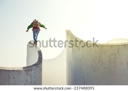 brave extreme man with backpack walking on a thin concrete wall