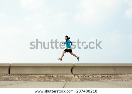 athletic sportsman running over concrete border near the ocean