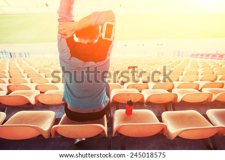 tired sweaty sportsman sitting on the chairs at stadium with sun shining and flare