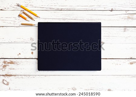 white blank wooden table with dark notebook and writing tools, top view