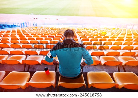 tired sweaty sportsman sitting on the chairs at stadium with sun shining