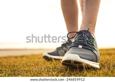 sportsman\'s legs standing on the grass in running shoes close up