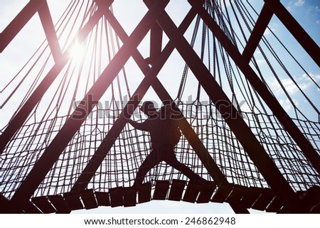 silhouette of a traveling man crossing over hanging bridge in bright sun
