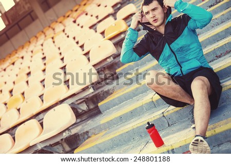 tired wet sportsman resting on the stairs at stadium