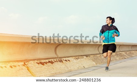 sportsman running near concrete fencing and looking far away