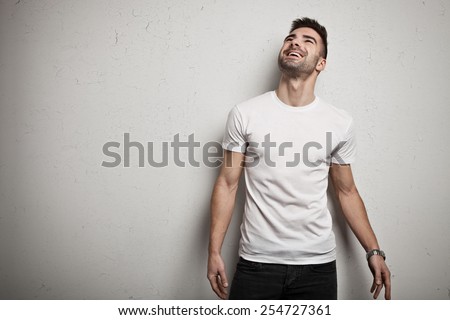 Smiling man in blank t-shirt, white grunge wall background