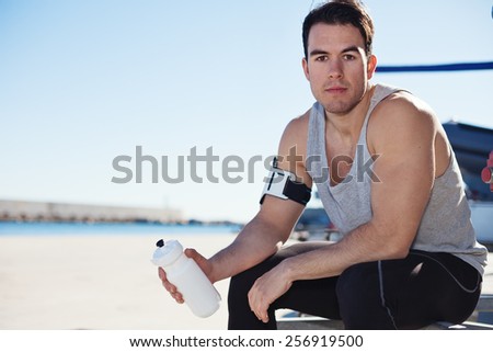 Portrait of fit male athlete with bottle of water