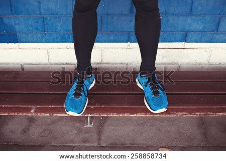 close-up of athlete\'s legs with running shoes standing on bench
