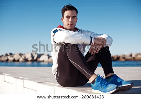 handsome athlete with armband relaxing after fitness outdoors
