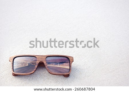 double exposure of wooden sunglasses  and desert road with white sand background