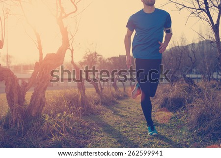 Athlete jogging in the park at sunset (little motion blur, intentional sun glare and vintage color)