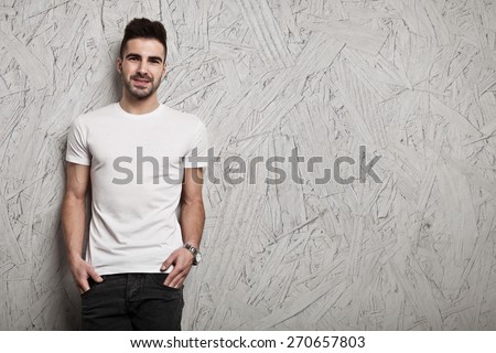 Smiling man in white blank t-shirt, and OSB wooden wall background