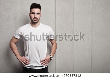 Serious man in white blank t-shirt, white concrete wall with pattern background
