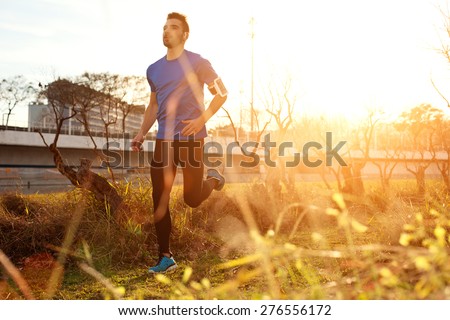 Male athlete running in the park at sunset (little motion blur, intentional sun glare)