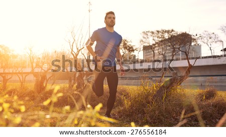 Male athlete running in the park at sunset (little motion blur, intentional sun glare)