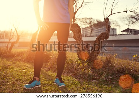 Young athlete standing in park at sunset (intentional sun glare)