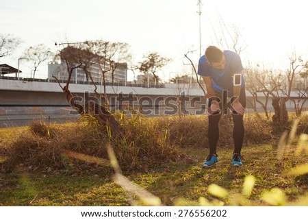 Tired runner resting in park after hard exercise (intentional sun glare)