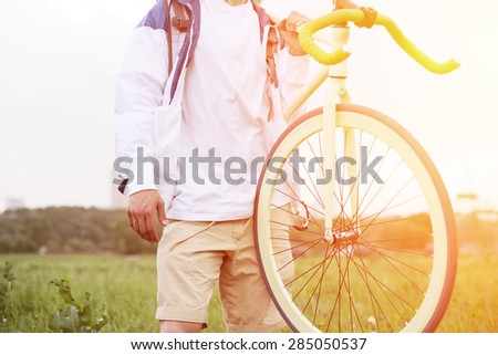 young man in blank t-shirt standing with bicycle on his shoulder (intentional sun glare and bright colors)