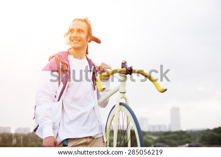 smiling man in blank t-shirt with bicycle in green field (intentional sun glare and bright color)
