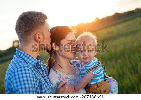 happy young family with baby spending time outdoors (intentional sun glare, lens focus on mother)