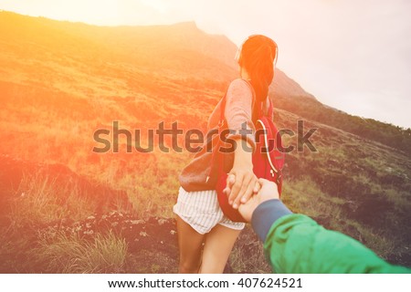 Brave and romantic adventure woman guiding man into the wild (intentional sun glare and vintage color)