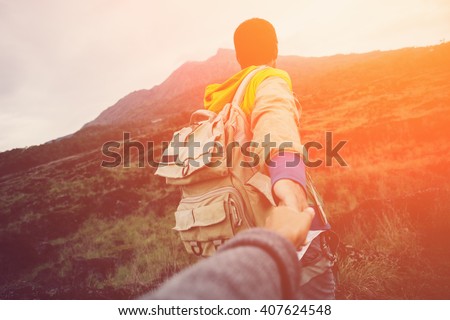 Brave and romantic traveler guiding woman to the mountain in the wild (intentional sun glare and vintage color)