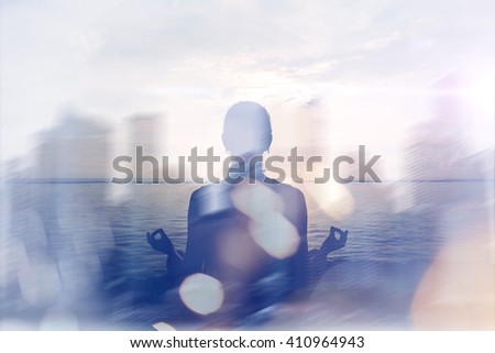 Yoga concept. Double exposure. Woman doing yoga practice on the beach and silhouette of modern city. Blurred effect, lens flare effect, intentional sun glare