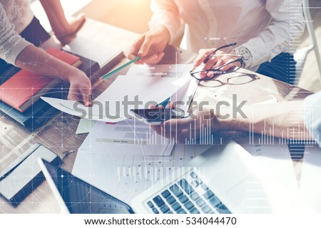 Business team brainstorming in office. Marketing plan researching. Paperwork on the table, laptop and mobile phone. Statistic graph overlay, icon innovation interface