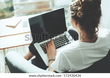 Casual woman manager sitting in her office workspace with computer and big bright window