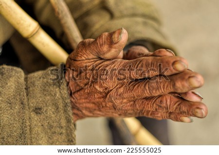 Wrinkled hands of an Indian holding a stick