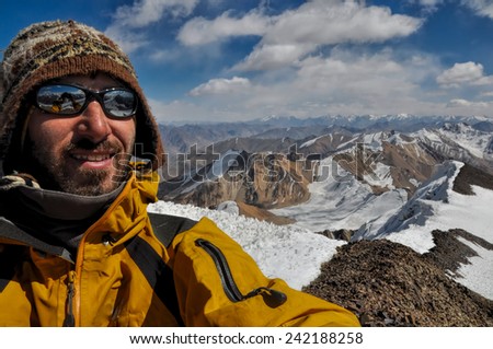 Smiling mountaineer on mountain summit in Pamir mountains in Tajikistan