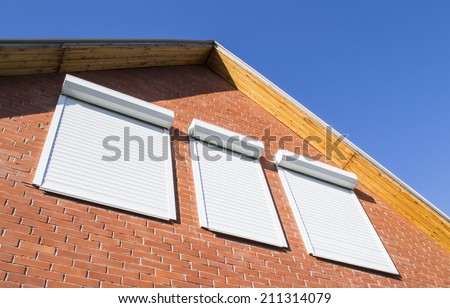 Red brick wall and window with rolling shutters