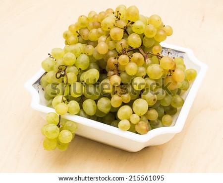 Brush of yellow grapes on a white dish