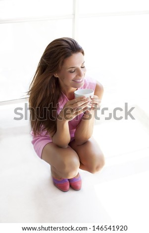 woman squatting with a cup of coffee