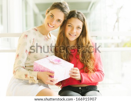 two sisters holding a gift and smiling