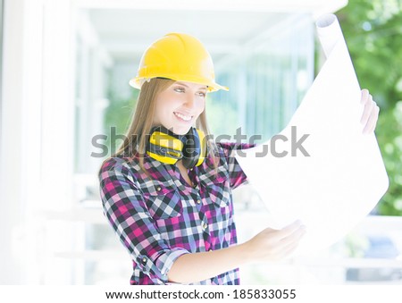 Young architect whit earmuffs, helmet and construction plans