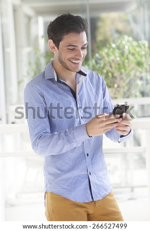 Young handsome man using smart phone dressed in casual outfit