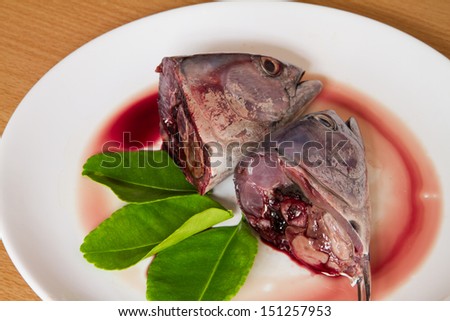 Fresh head fish with lime leaves on white dish.